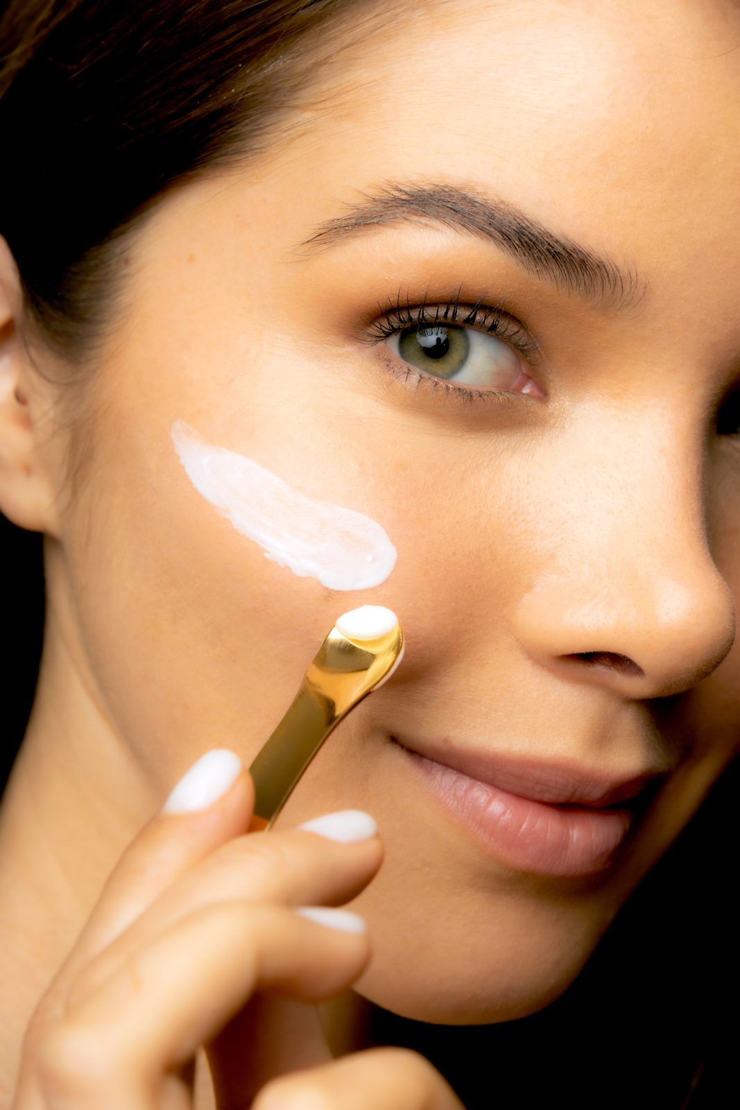 Model applying Cotrini night cream to her cheek with the gold spatula